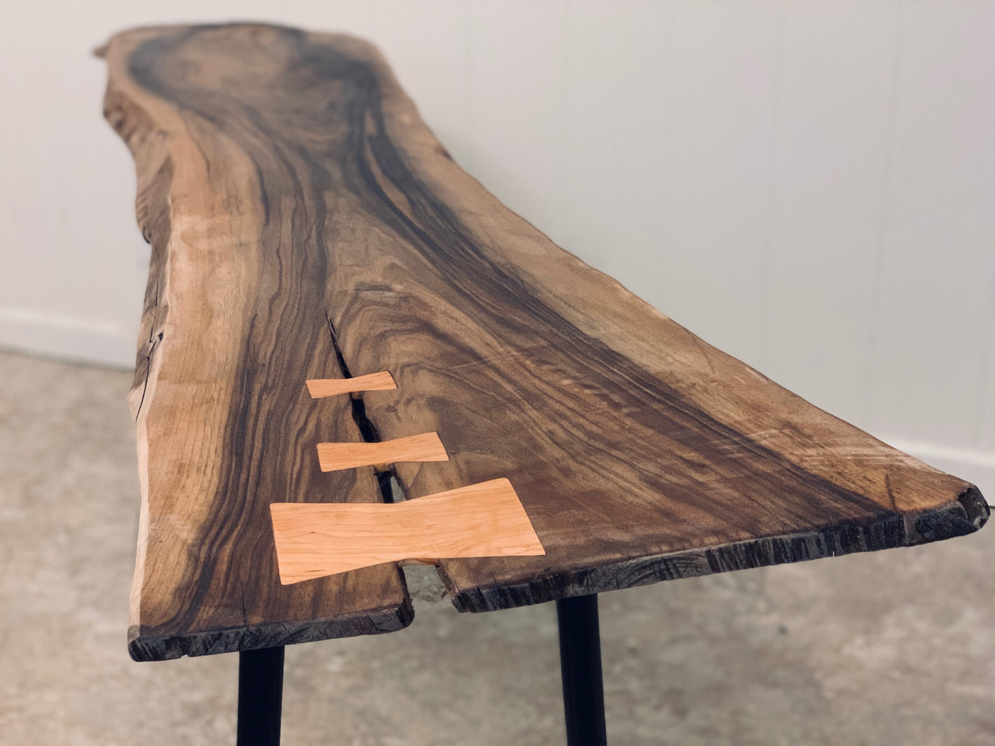 Picture of a live edge solid walnut slab with cherry butterfly joints and black metal legs made by oregon handcraft